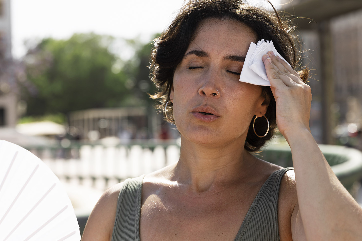 mujer en el exterior con mucho calor se pasa un pañuelo por la frente para quitarse el sudor